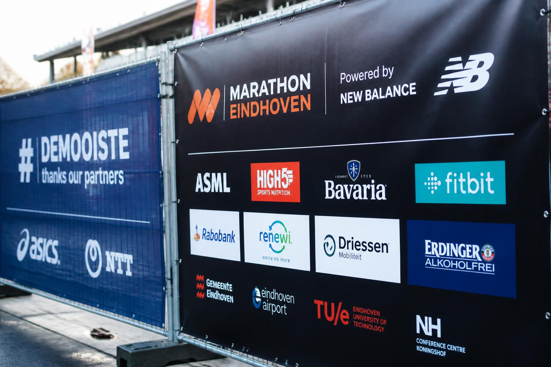 Sponsorbanners op hekwerk langs het parcours van een marathon in Eindhoven